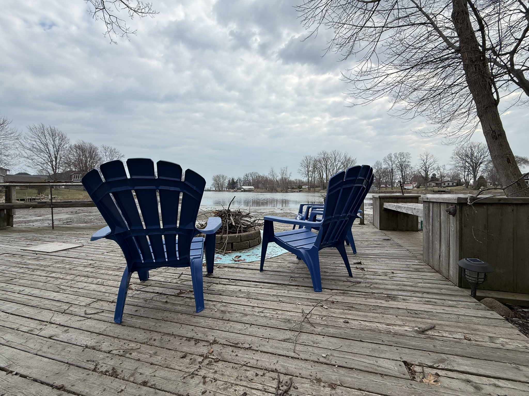 Deck with blue Adirondack chairs and fire pit, creek in background