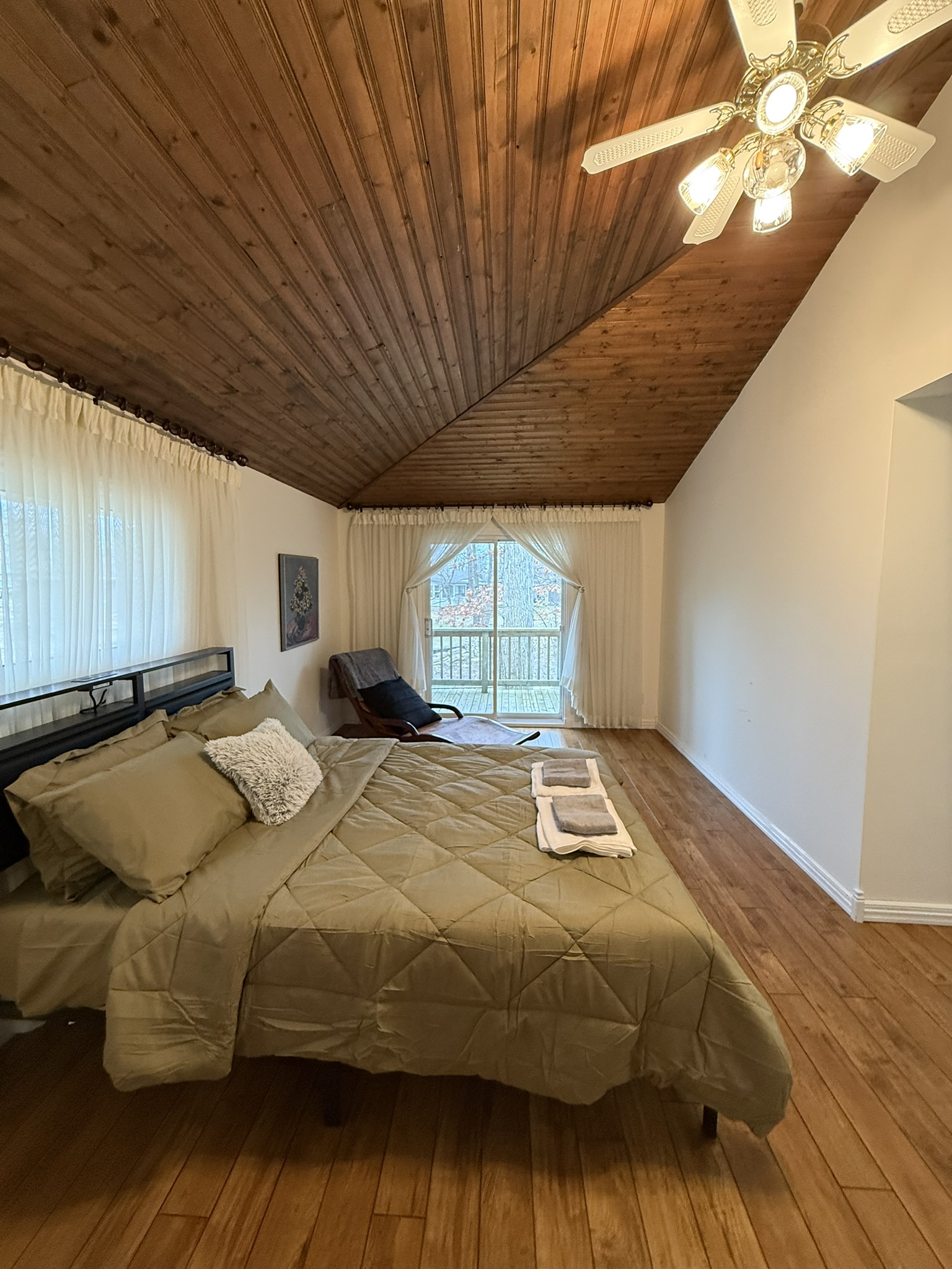 Primary bedroom with wood cathedral ceiling and queen bed
